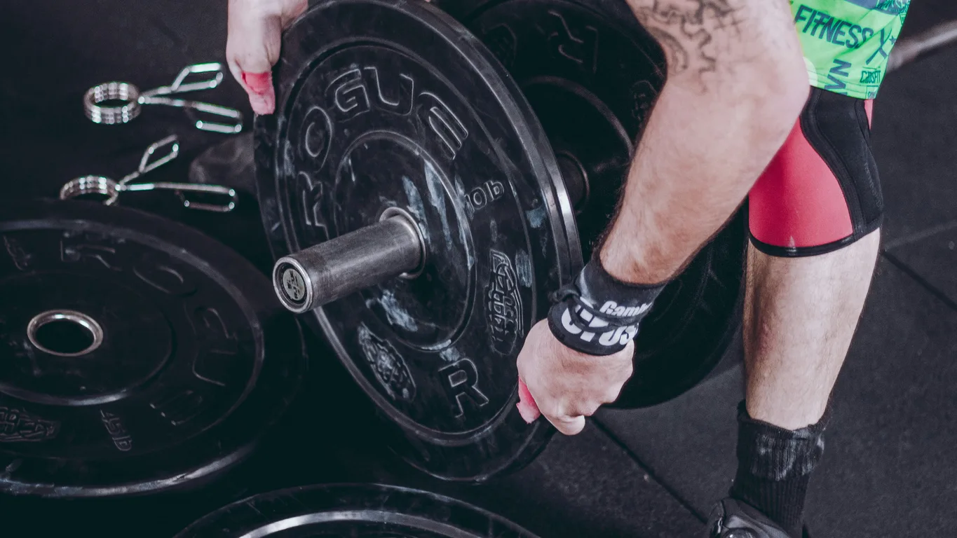 Mann beim Kreuzheben mit schwerer Langhantel im Fitnessstudio