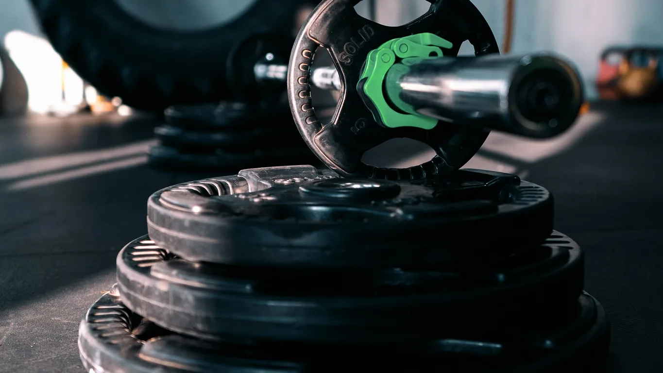 Mann bei kontrollierter Kniebeuge mit leichtem Gewicht in sonnigem Fitnessstudio