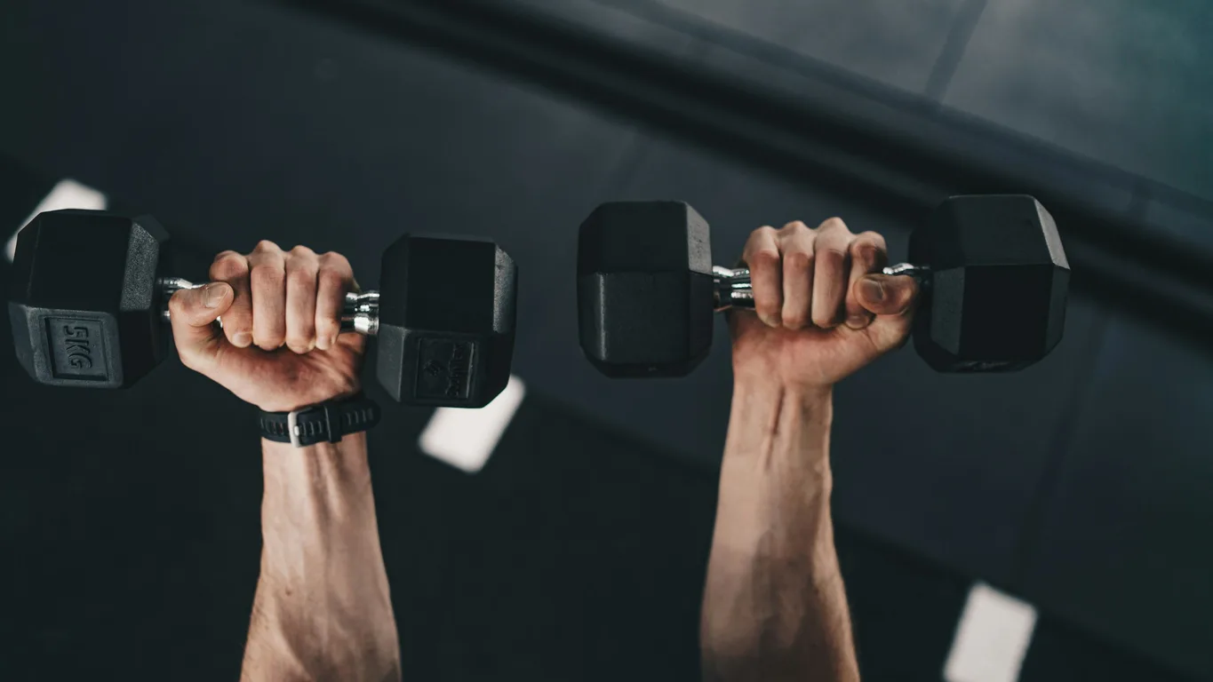 Frau greift zur nächsten Kurzhantel am Rack im Fitnessstudio