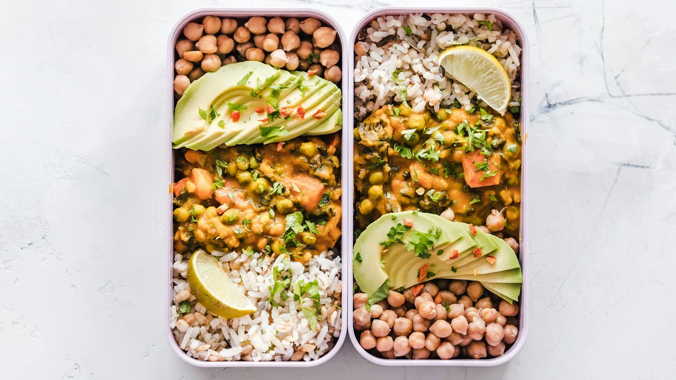 Meal-Prep-Boxen mit Reis, Hähnchen und Gemüse auf Holztisch