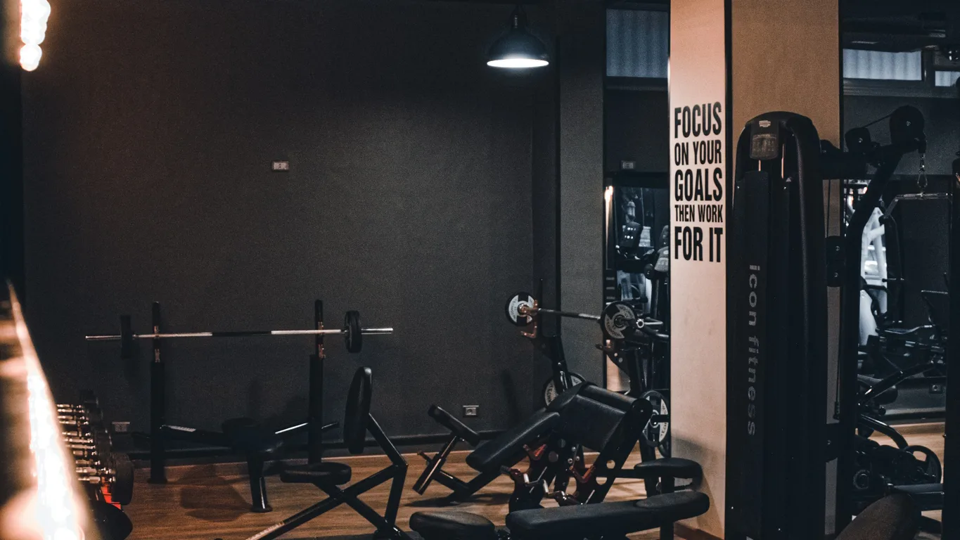 Mann beim einarmigen Kurzhantel-Rudern auf einer Flachbank im Fitnessstudio