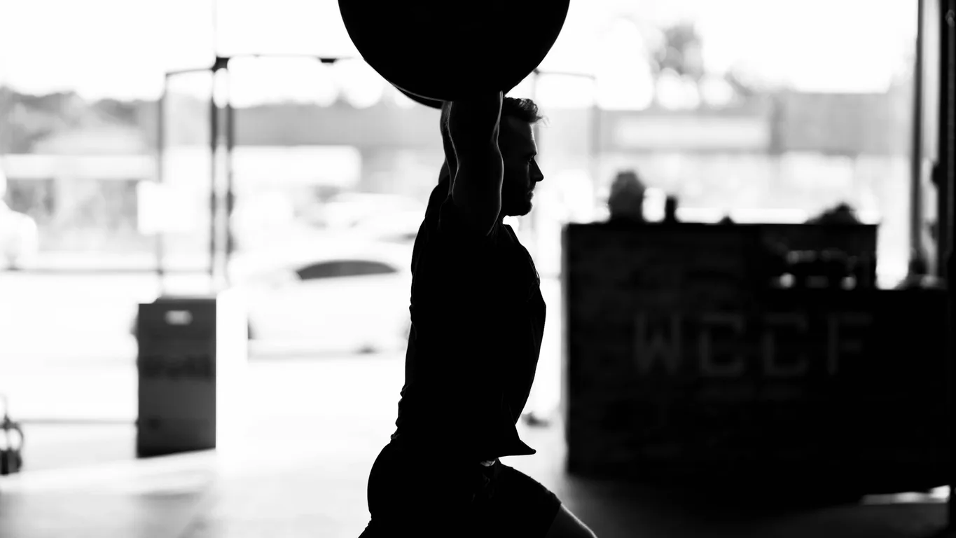 Frau sitzt nachdenklich auf einer Gym-Bank nach dem Training mit Wasserflasche