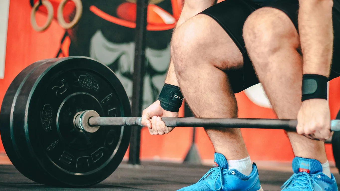 Langhantel, Kurzhanteln und Kettlebell nebeneinander auf Gym-Boden von oben