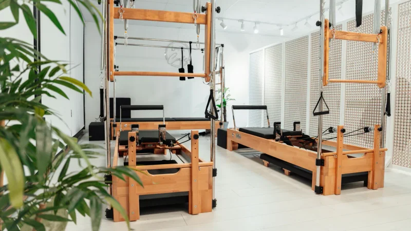 Helles Pilates-Studio mit hölzernen Reformern, Federn und Pflanzen