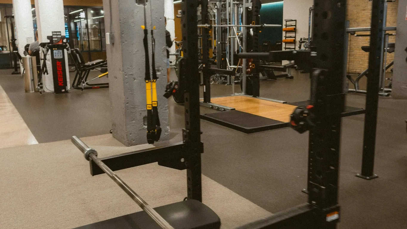 Mann bei der Kniebeuge im Power Rack, Seitenansicht, warmes Licht
